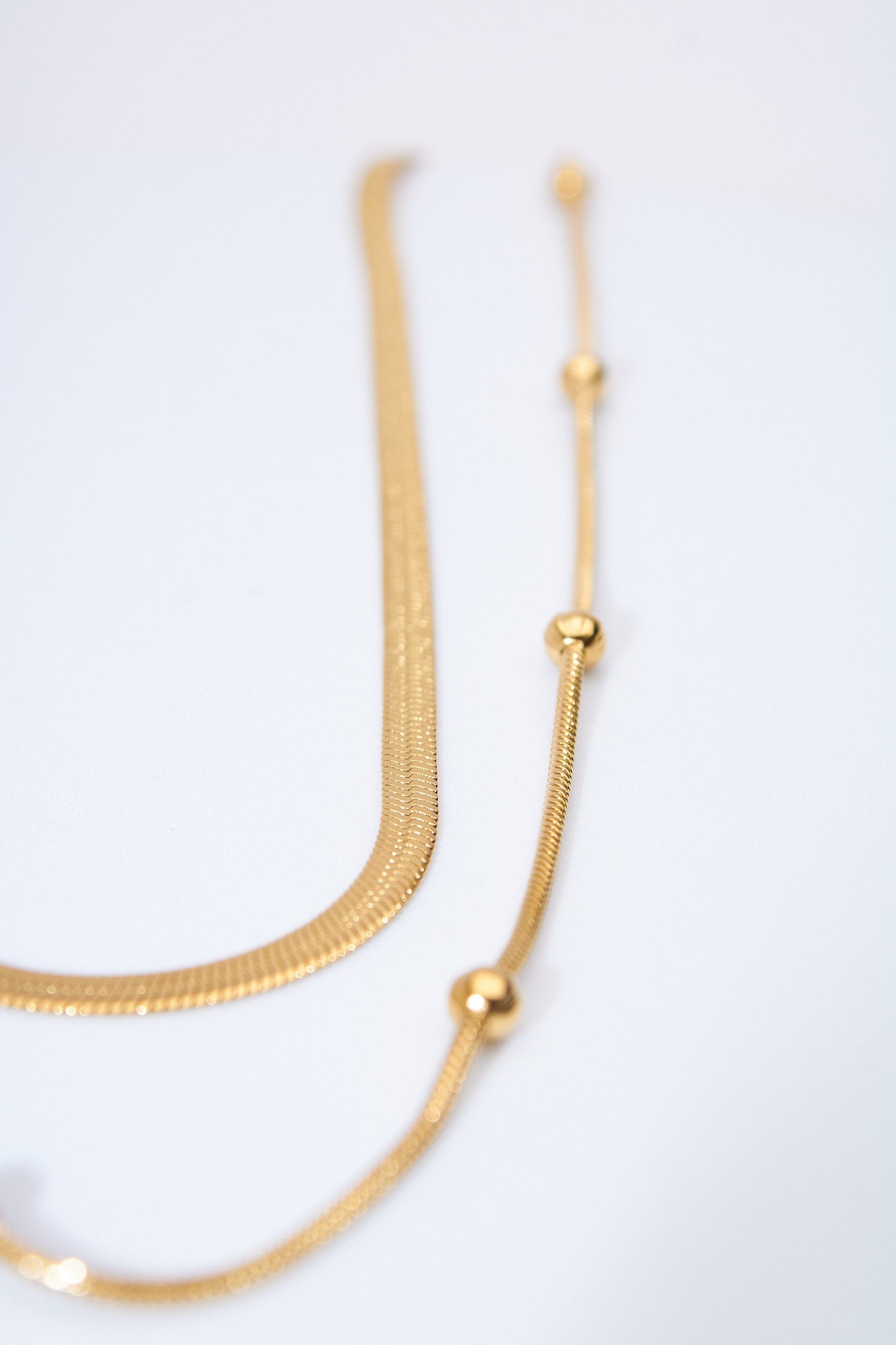 Collar doble capa — cadena plana + cadena con bolitas móviles, baño dorado