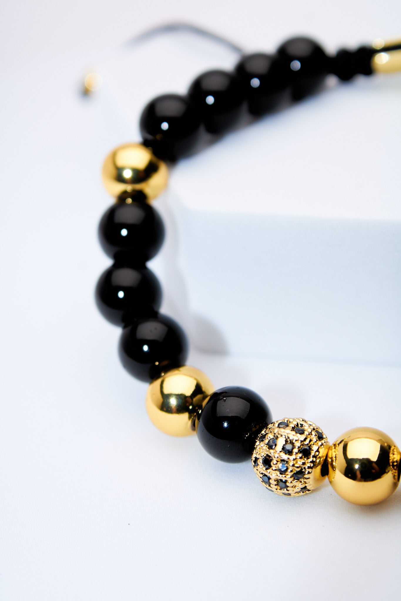 Pulsera ajustable ónix y bolitas doradas con pavé negro