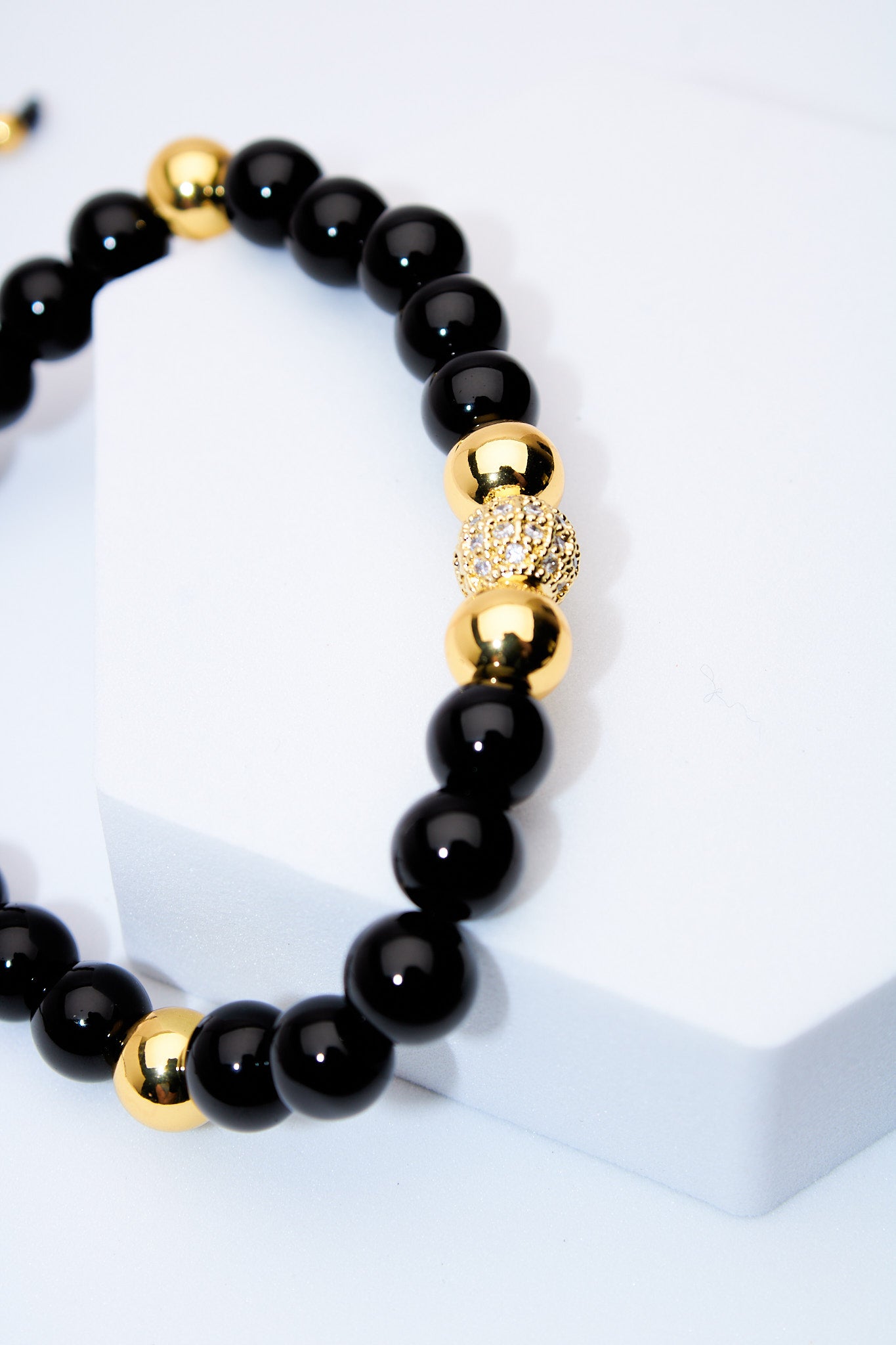 Pulsera ajustable ónix con bolitas doradas y centro pavé