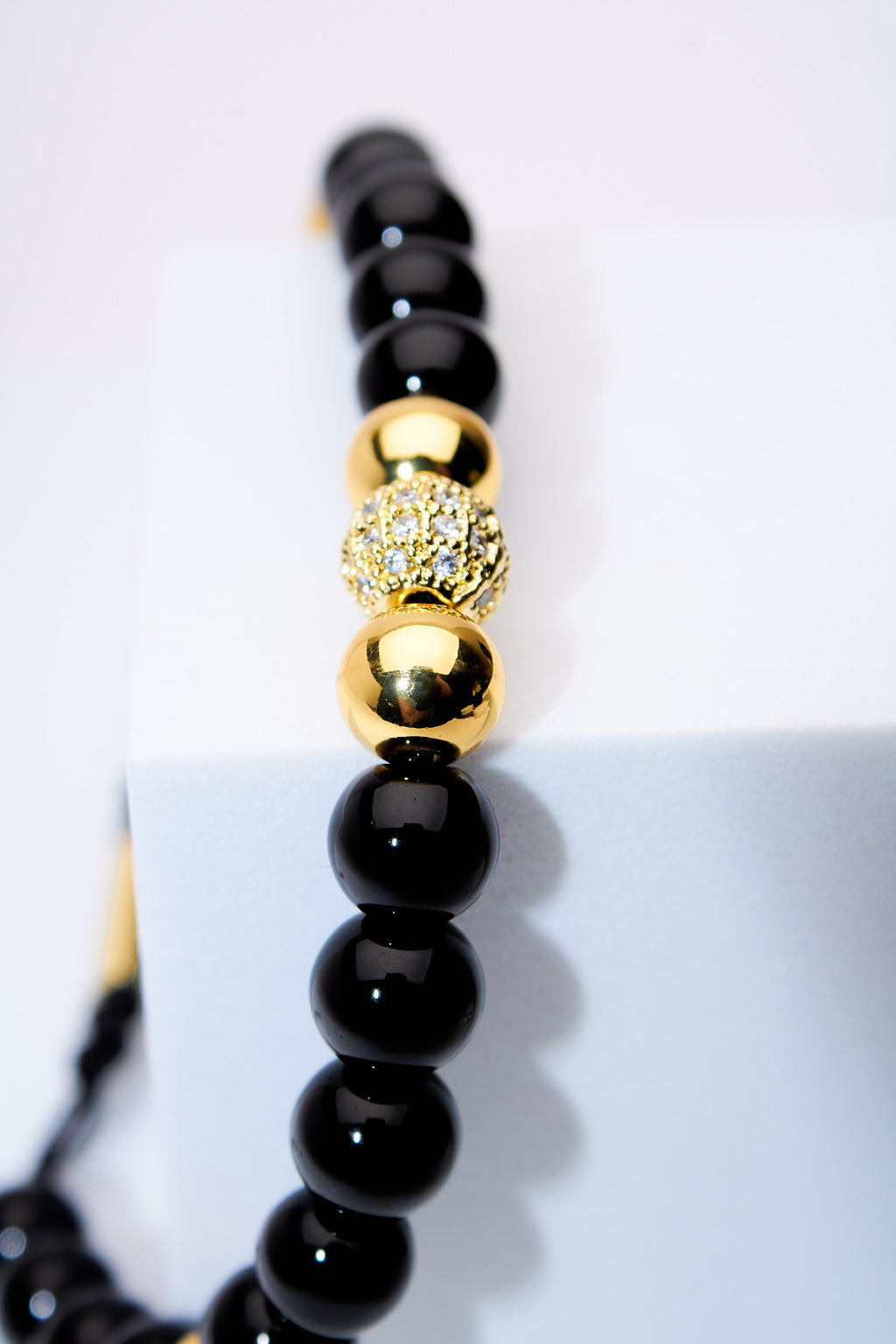 Pulsera ajustable ónix con bolitas doradas y centro pavé