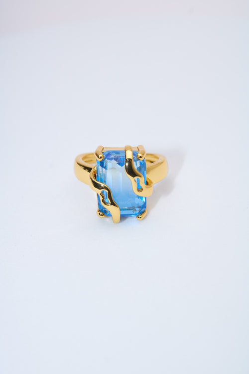 Anillo con piedra azul facetada — baño dorado
