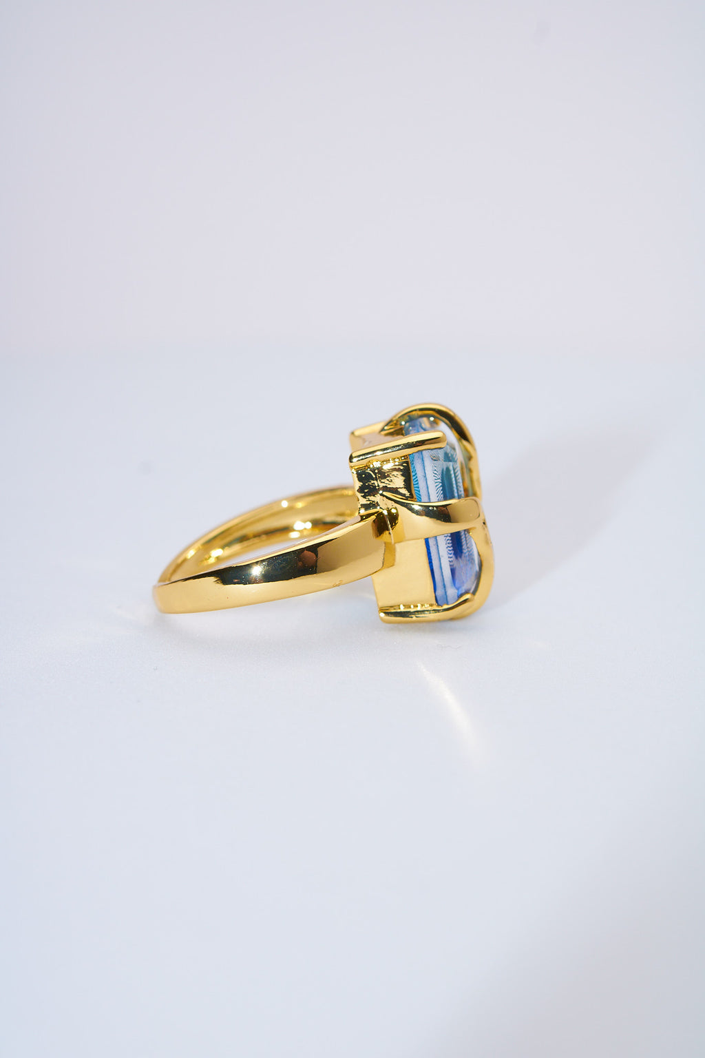 Anillo con piedra azul facetada — baño dorado