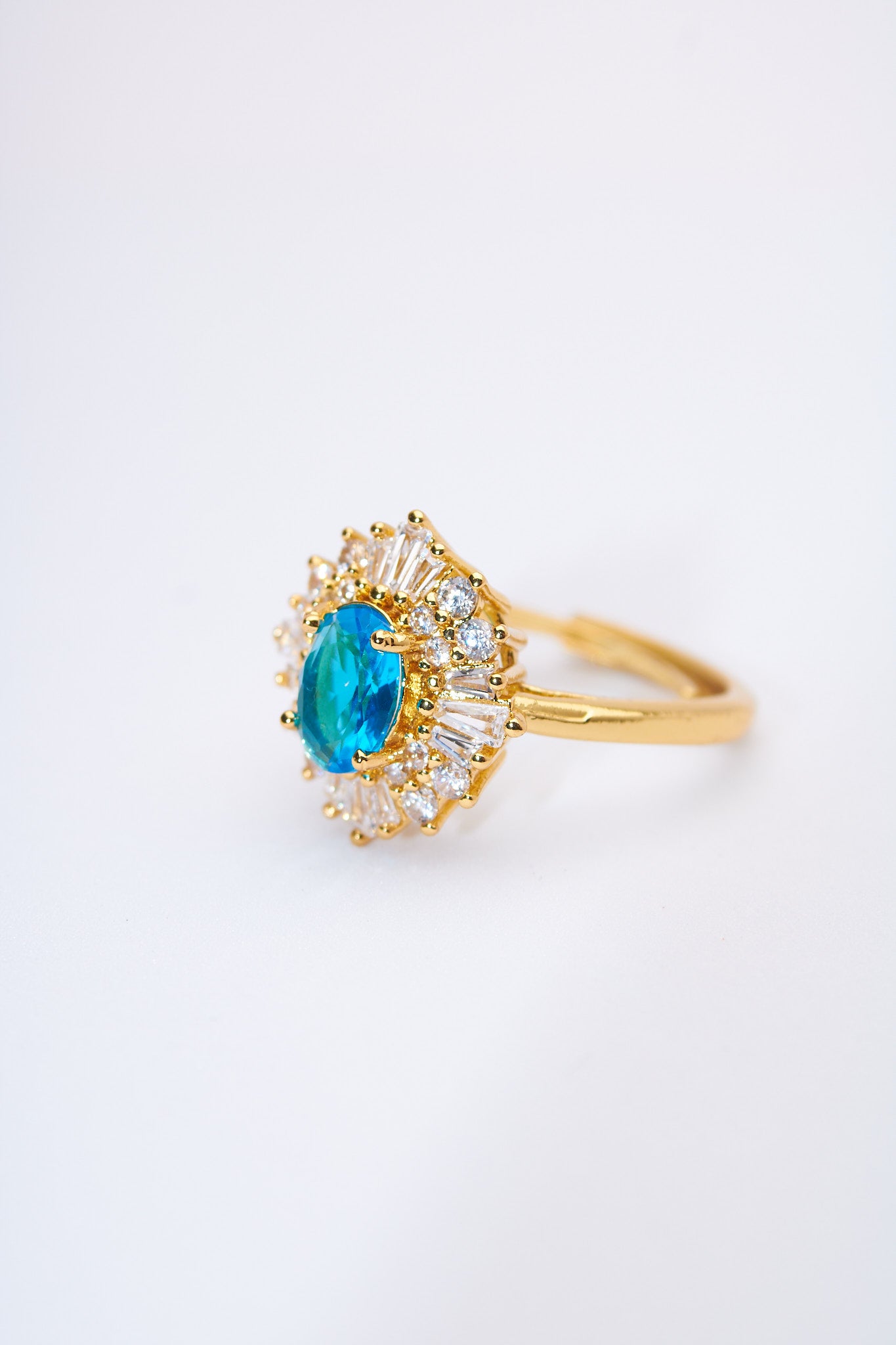 Anillo solitario floral con piedra azul y halo de cristales — baño dorado