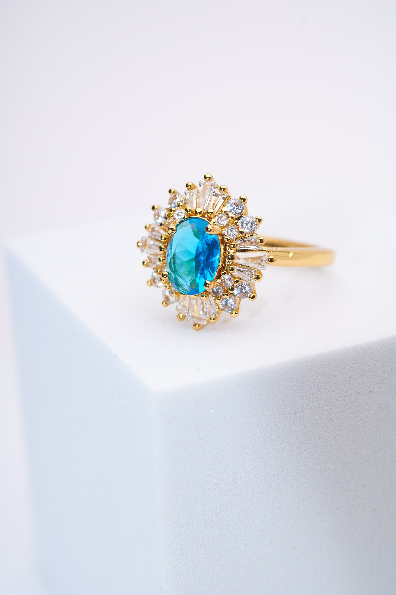 Anillo solitario floral con piedra azul y halo de cristales — baño dorado