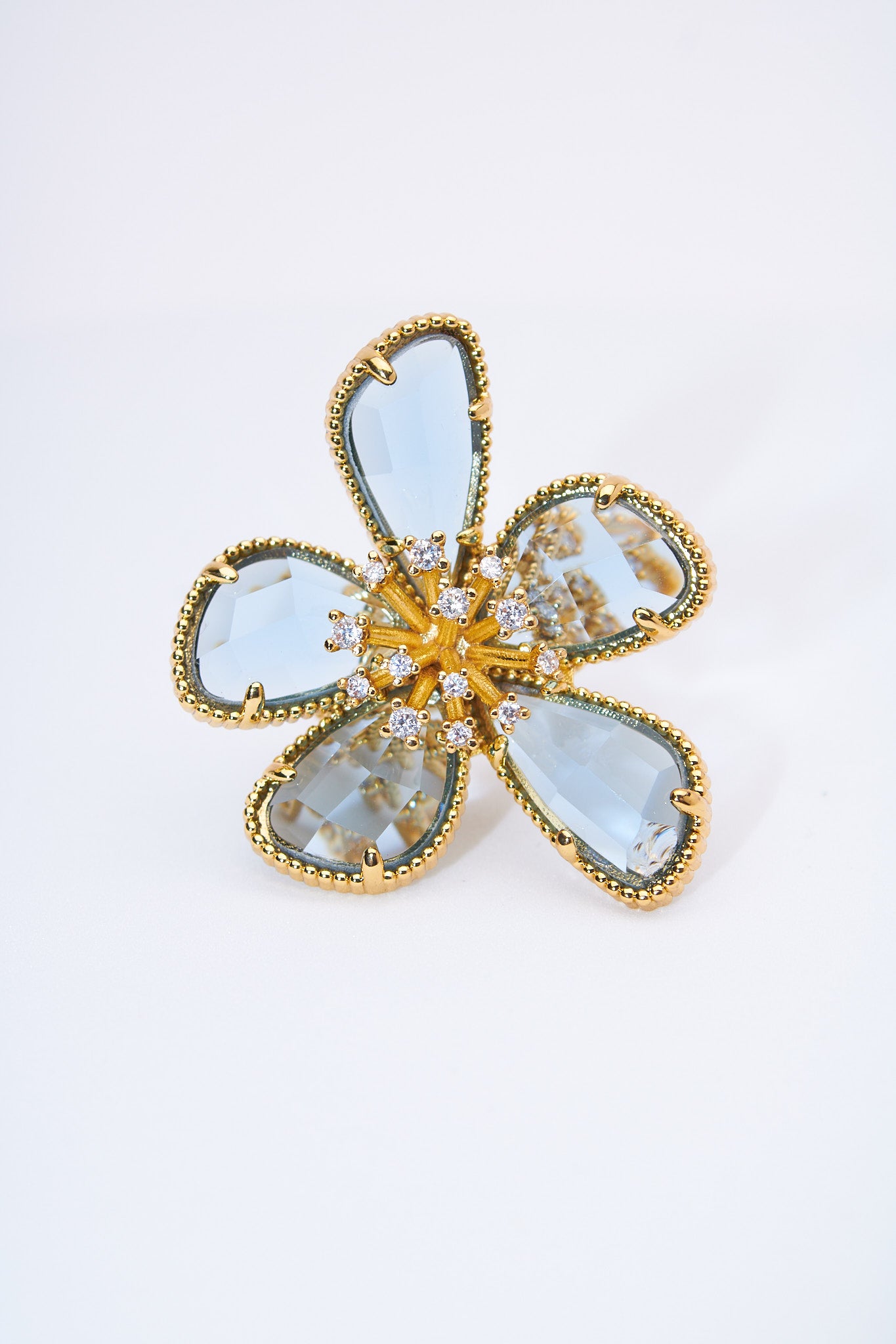 Anillo flor con pétalos lágrima azul claro — baño dorado