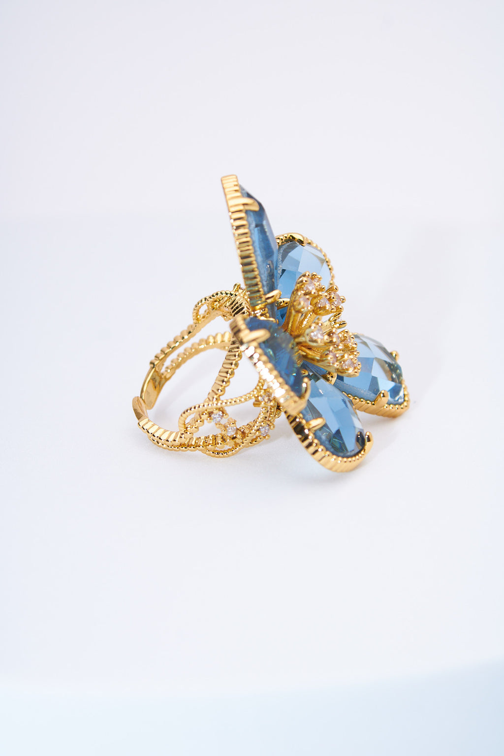 Anillo flor con pétalos lágrima azul claro — baño dorado