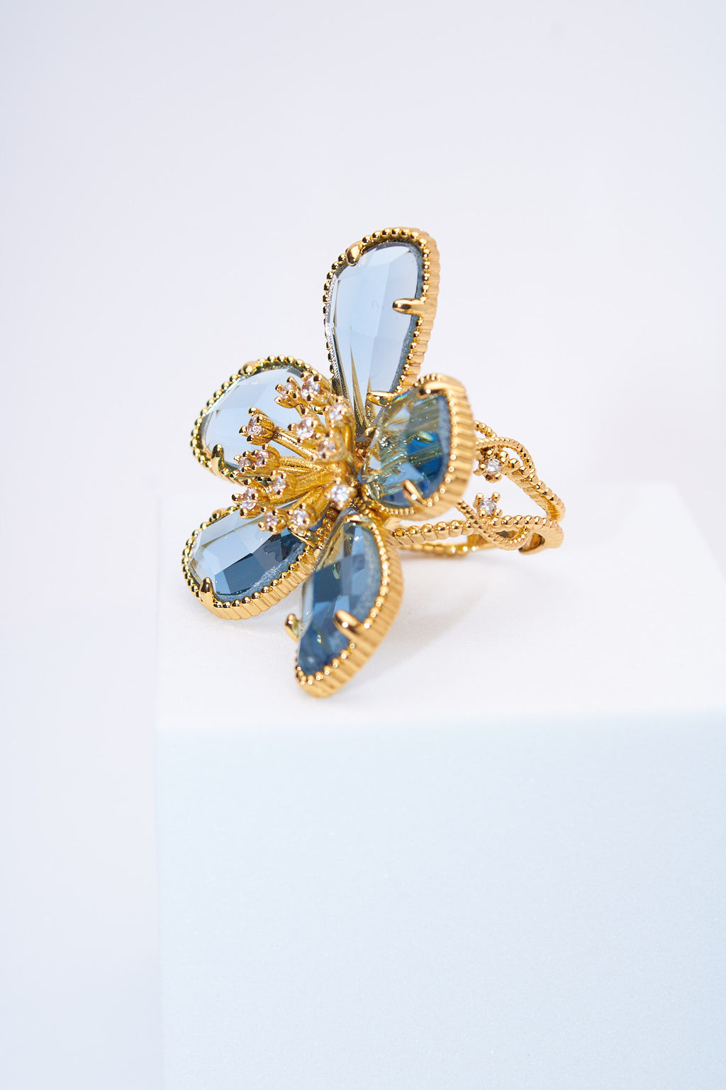 Anillo flor con pétalos lágrima azul claro — baño dorado